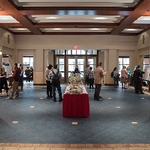 The Gradaute Showcase, with many student posters and presenters, a buffet table, and people moving around the room